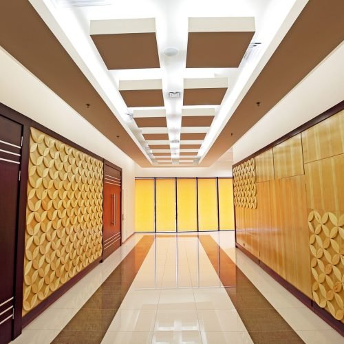 Elegant corridor in a luxury hotel featuring modern geometric wall decor and bright lighting.